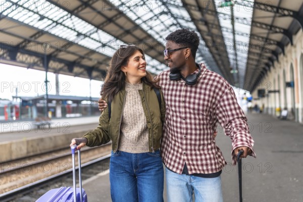 Young multi ethnic couple walking hand in hand with luggage on a bustling train station platform, radiating happiness and excitement for their journey
