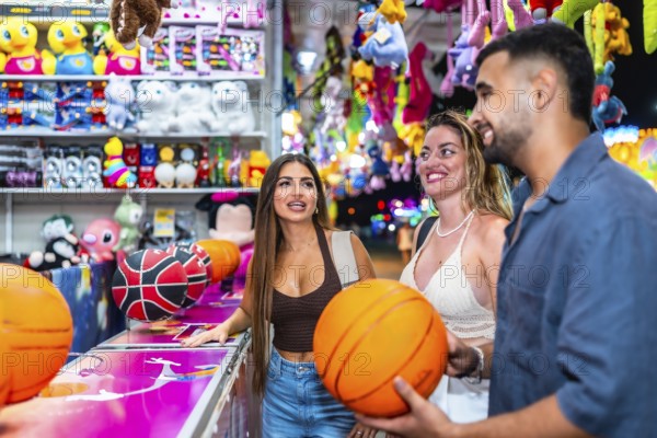Three friends having fun playing a basketball game at an amusement park, enjoying their summer vacation together