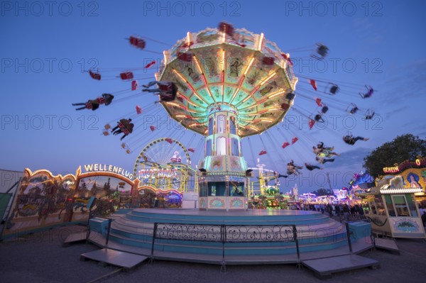Lively carousel illuminated at a night fair, chain carousel, spring festival, Cannstatter Wellenflug, illuminated, blue hour, Cannstatter Wasen, Bad Cannstatt, Stuttgart, Baden-Württemberg, Germany