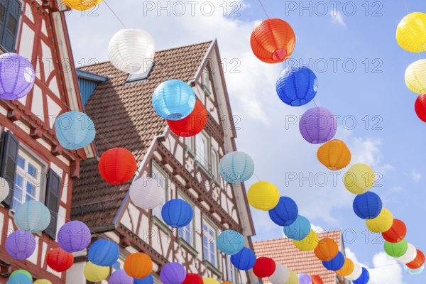 Lively balloons float above traditional half-timbered houses in a clear blue sky, Calw, Black Forest, Germany