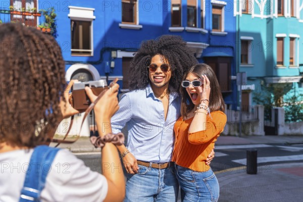 Young tourist taking a picture of her surprised friends posing in a colorful street during summer holidays