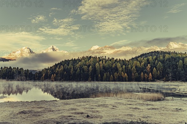 Lake Staz near Sankt Moritz in the Engadin in Switzerland. Morning atmosphere with fog in autumn. Water reflection and snow-covered mountains in the background