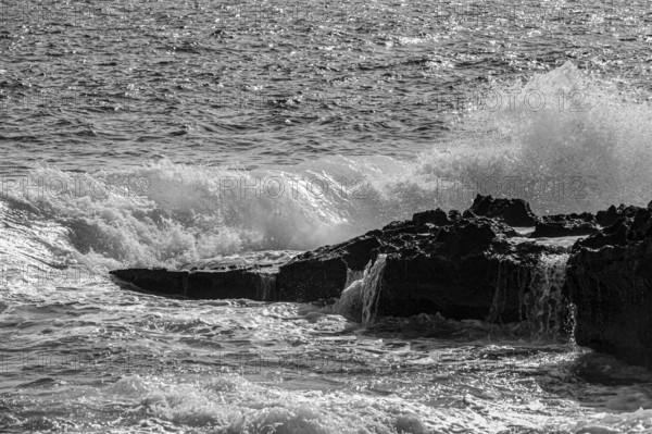 Rugged rocky coast and foaming spray, on Stecci beach, black and white photograph, near Capoliveri, Elba Island, Tuscan Archipelago National Park, Tuscany, Italy