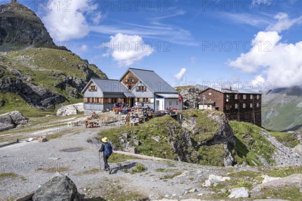Mountaineer in front of mountain hut Cabane de Prafleuri in mountain landscape, Valais, Western Alps, Switzerland