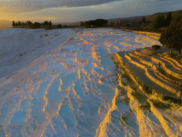 Landscape with terraces and water that glows orange and blue in the sunset light, aerial view, sinter terraces, lime sinter terraces, travertine terraces, Pamukkale, Denizli, UNESCO World Heritage Site, Anatolia, Turkey