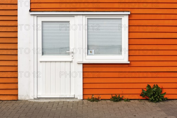 Colourful lobster shack, orange wooden façade with door and window, registry office sticker, façade detail in the harbour, Heligoland, Schleswig-Holstein, Germany
