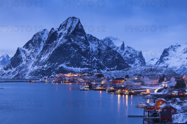 Fishermen's Village in front of snowy mountain range at the coastline in winter, Lofoten, Norway