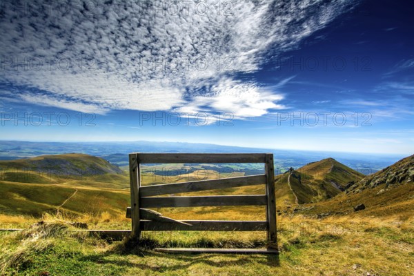 A wooden barrier stands at the edge of Sancy Mountain, providing a breathtaking view of the Auvergne volcanoes natural park, Puy de Dome, Auvergne Rhone Alpes, France