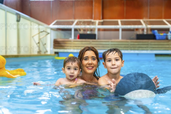 Happy mother enjoying time in the swimming pool with her sons, playing joyfully with colorful inflatable toys and creating lasting memories
