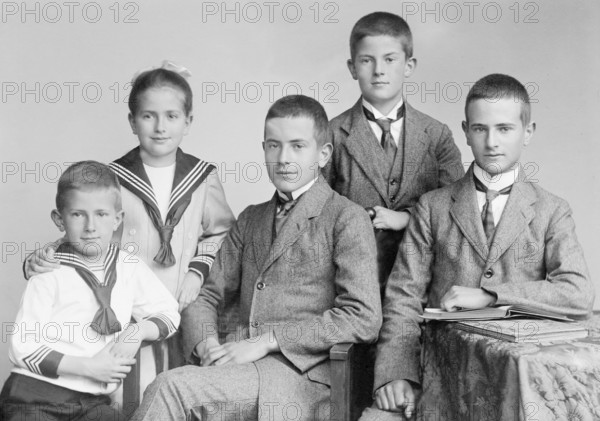 Group photo of five siblings, 1930s, Four boys and a girl in traditional suits and dresses pose formally for a photo, Historical photo