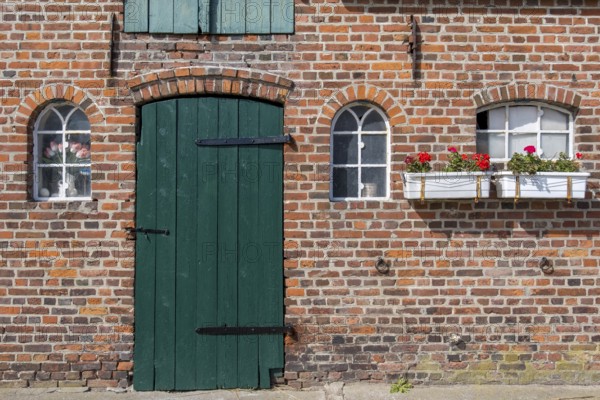 Nostalgic brick wall with green door and white windows, decorated with flower pots, Föhr, Nordfriesland, Schleswig-Holstein, Germany