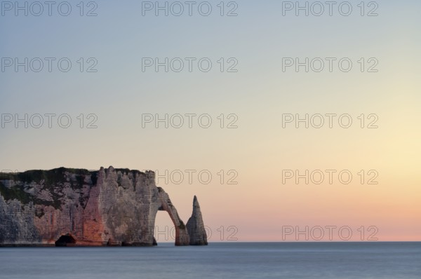 Rock arch Falaise or Porte d'Aval and rock needle Aiguille, illuminated, illuminated, Étretat, sea, steep coast, cliffs, chalk cliffs, alabaster coast, La Côte d'Albâtre, sunset, evening mood, atmospheric, Normandy, Seine-Maritime, France