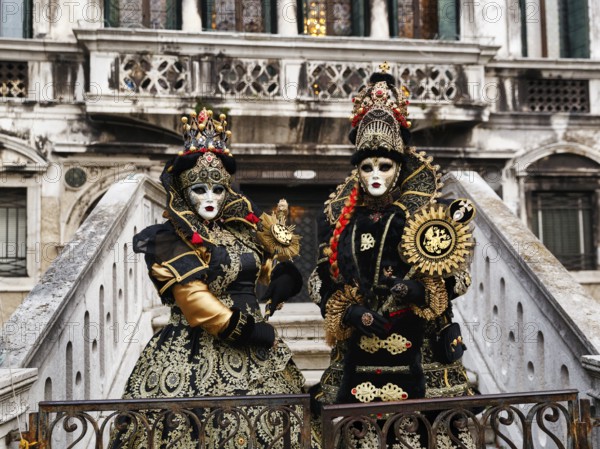 Two people in costume posing on a staircase, Venetian costumes with masks, Carnival in Venice, Italy