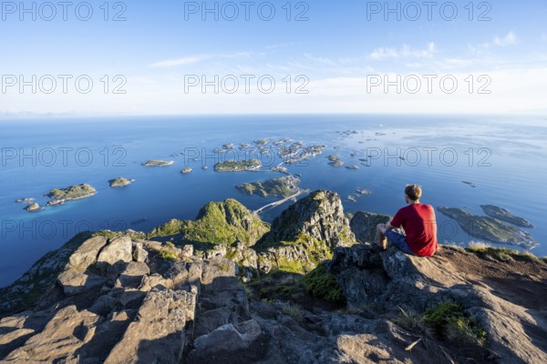 View of numerous small rocky islands with houses, mountaineers on the summit of Festvågtind, view of Henningsvær, Vågan, Lofoten, Nordland, Norway