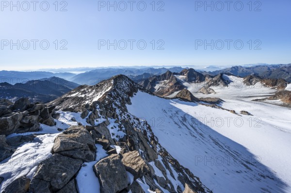 Narrow rocky ridge at the Wilder Freiger summit, picturesque high mountain landscape with snow, view of Übeltalferner glacier and rocky mountain peaks Königshofspitz and Sonklarspitze, Stubai Alps, South Tyrol, Italy