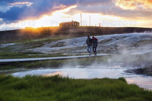 Walker on wooden path, sulphur vapour, geothermal area Hveravellir, sunset, icelandic highlands, Suðurland, Sudurland, Iceland