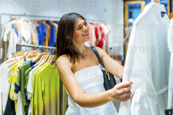 Happy customer smiling while holding a stylish white dress, enjoying the vibrant atmosphere of a fashion store during a shopping trip