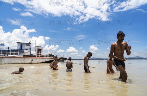 People bathe in the Brahmaputra River to seek relief from the intense summer heat in Guwahati, India, on June 26, 2025