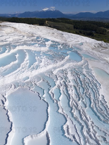 Cascading terraces of turquoise water and white limestone in the foreground, mountains in the background, aerial view, sinter terraces, limestone sinter terraces, travertine terraces, Pamukkale, Denizli, UNESCO World Heritage Site, Anatolia, Turkey