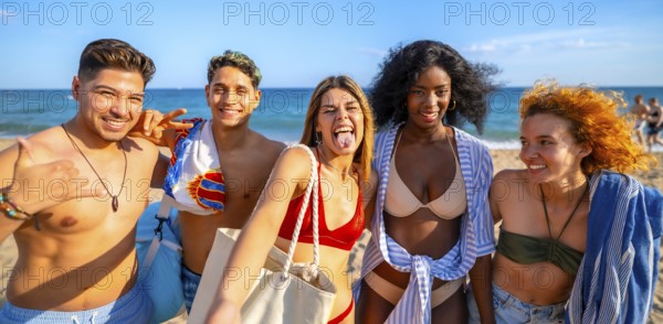 Five multi ethnic friends are having fun taking a selfie on the beach, sticking out their tongues and making funny faces