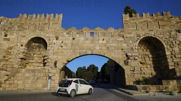 Arsenal Tor, Modern car drives through a historic stone gate on the road, harbour area, Rhodes Town, Rhodes, Dodecanese, Greek Islands, Greece