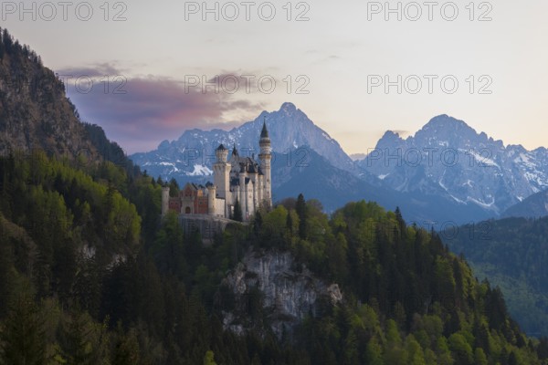 Neuschwanstein Castle against an impressive Alpine backdrop at dusk, Schwangau near Füssen, Ostallgäu district, Swabia, Bavaria, Germany