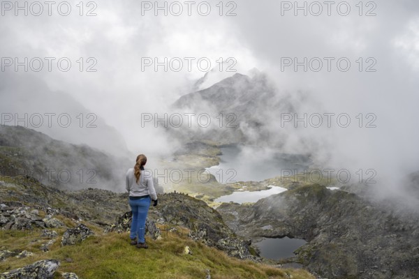 Mountaineer in front of mountain lakes Wangenitzsee and Kreuzsee, cloudy mountain peaks in the morning, Schober group, Hohe Tauern National Park, Carinthia, Austria