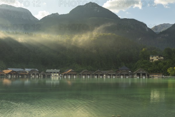 Mystical morning at Königssee in Schönau with boathouses. Sunrise and beautiful wafts of mist over the Königssee in the basin