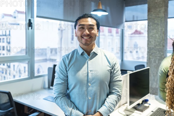 Portrait of a smiling asian businessman standing in a bright, modern office, conveying confidence and professionalism