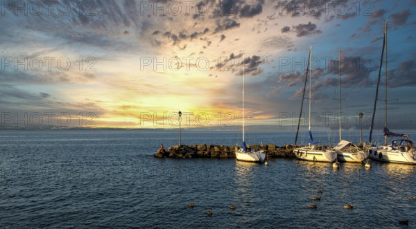 Harbour at Yvoire on Lake Leman during sunset with boats and serene waters in Haute Savoie, Auvergne-Rhone-Alpes, France
