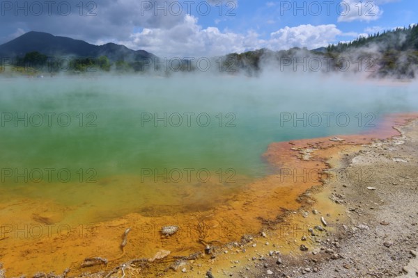 A steaming hot spring with an orange-coloured rock edge, Champagne Pool thermal lake, Wai-O-Tapu Thermal Wonderland, Rotorua, North Island, New Zealand