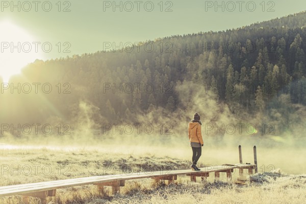 Young woman at Lake Staz near Sankt Moritz in the Engadine in Switzerland. Morning atmosphere with fog in autumn. Reflection of water
