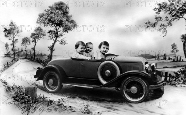 Three babies in a car, 1920s, Three children in a vintage car on a rural road, surrounded by trees, Historical photo