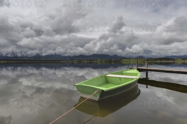 Storm clouds at sunset, a green rowing boat lashed to the wooden jetty, Hopfensee, Hopfen am See, near Füssen, Ostallgäu, Allgäu, Bavaria, Germany