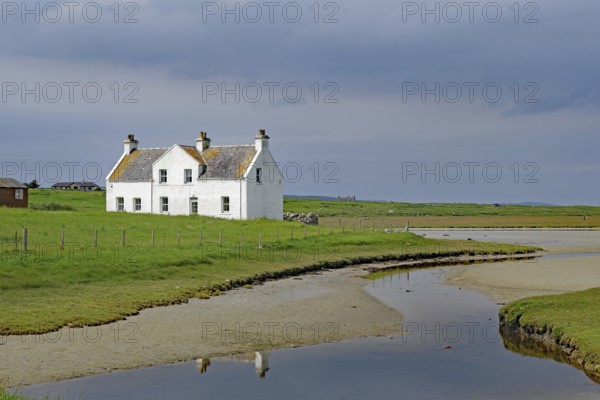 Lonely white house in a green field under a cloudy sky, Isle of Harris, Hebrides, Scotland, United Kingdom
