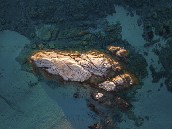 A rock formation rises out of the turquoise-blue water on the Costa Rei, a stretch of coastline on the Italian Mediterranean island of Sardinia. (Aerial photo taken with a drone), Monte Nai, Costa Rei, Sardinia, Italy