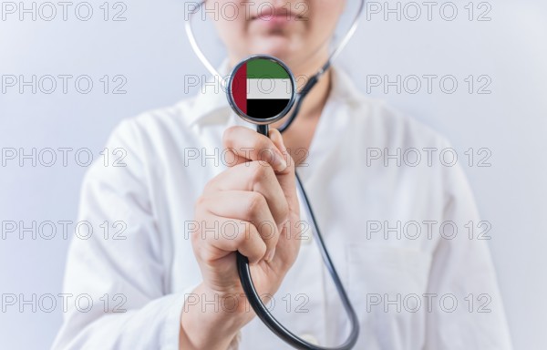 Female doctor holding stethoscope with United Arab Emirates flag. National health system of United Arab Emirates