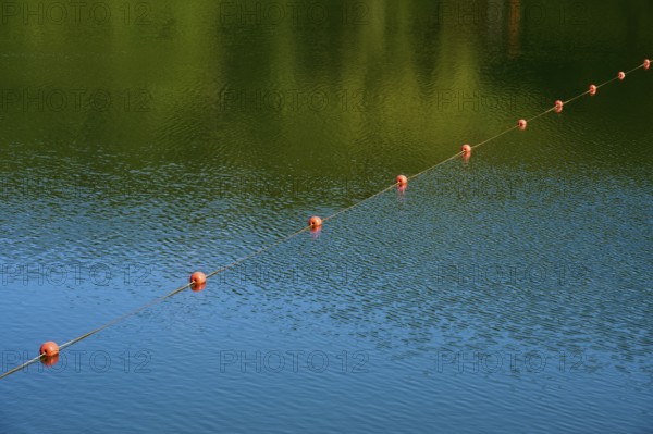 Row of red buoys on calm, green-blue water, summer, Rursee, Rurberg, Simmerath, Eifel National Park, North Rhine-Westphalia, Germany