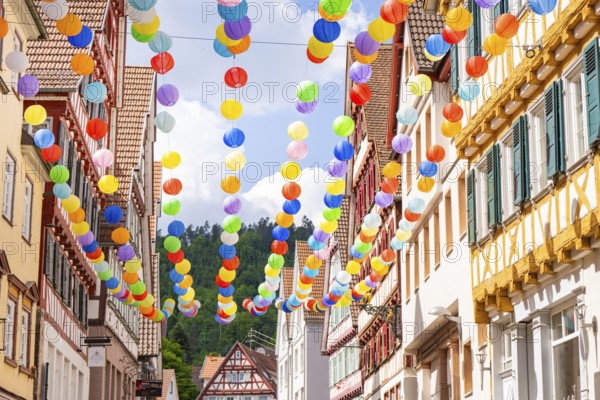 Colourful balloons decorate a narrow street in a picturesque old town under a sunny sky, Calw, Black Forest, Germany