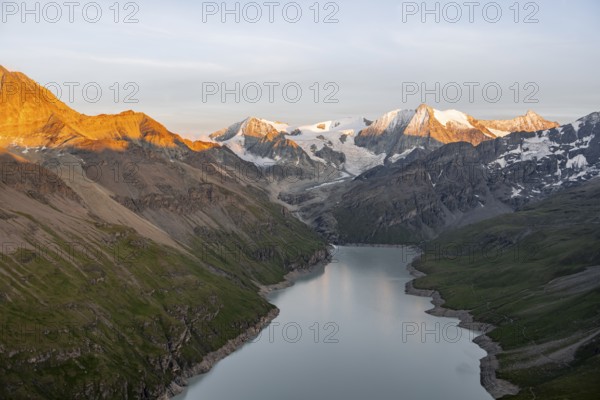 View at the summit of Mont de la Blana, alpenglow at sunset, view of a blue mountain lake, Lac des Dix reservoir, behind mountain peak Mont Blanc de Cheilon with glacier, Hérménence, Valais Alps, Valais, Switzerland