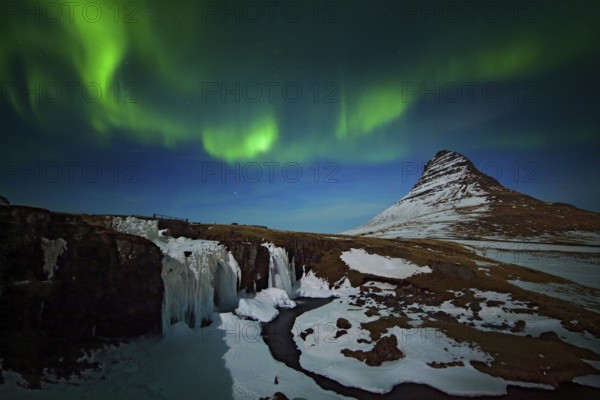 Aurora Borealis from Iceland. Beautiful green Northern Lights on the dark blue night sky with peak with snow, Kirkjufell, Iceland