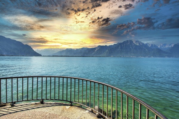 Golden light reflects on the calm waters of Lake Leman as clouds gather over the mountains in Montreux. A tranquil evening captures the charm of Canton de Vaud, Switzerland