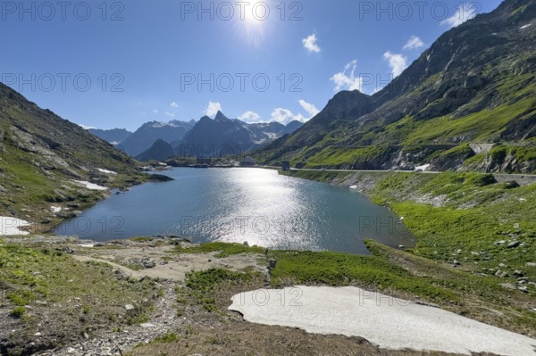 View from Swiss territory to Italian territory over mountain lake Lac du Grand Saint Bernard on top of pass road mountain pass alpine pass border pass Great St. Bernard Pass, pass road, mountain pass above tree line early summer, tree line, Great St. Bernard Pass, Valais, Switzerland, Valle d'Aosta region, Italy