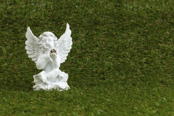 A white angel figure sits on green grass