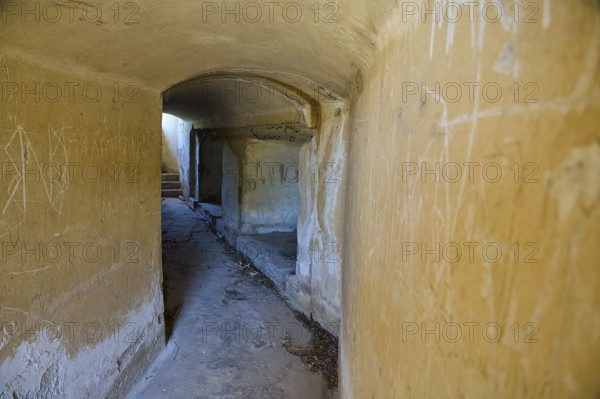 Long corridor with weathered walls leading into the darkness, mysterious and abandoned, Italian anti-aircraft position, ground defence position, PL306 with 6 cannons, WW2, Vigla Mountain, Vigla, above Lakki, Lakki, Leros, Dodecanese, Girechian Islands, Greece