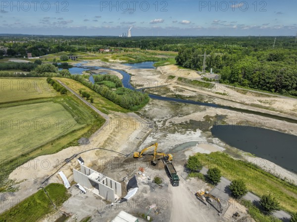 Dortmund, Castrop-Rauxel, North Rhine-Westphalia, Germany - River renaturalisation, renaturation of the Emscher, flood retention basin HRB Mengede. A new floodplain landscape is being created at the Emscher-Auen farm, expanding the area for flood protection during heavy rainfall and for biodiversity. The previously straightened Emscher is being given curves again and can meander through its new floodplain. Following the construction of a parallel sewer, the Emscher has been completely free of sewage since 2022. The river was previously an open, above-ground combined sewer with rainwater and wastewater. Heimanngraben inlet at the front, construction of a bridge over the ditch