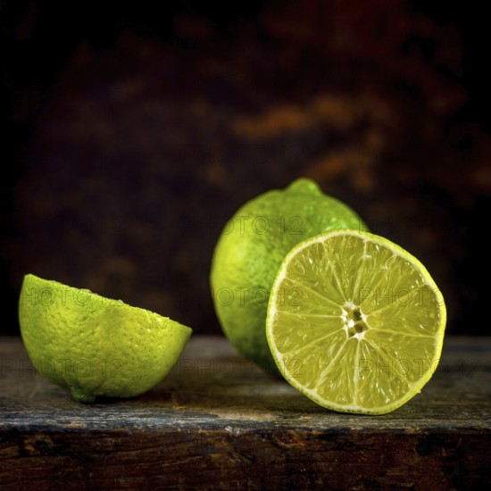 Close-up view of fresh lemons and their slices set against a brown background, showcasing the vibrant yellow color and juicy texture ideal for culinary uses
