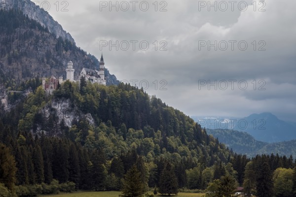 The impressive Neuschwanstein Castle on a wooded mountain under a fascinating cloudy sky, Schwangau, Bavaria