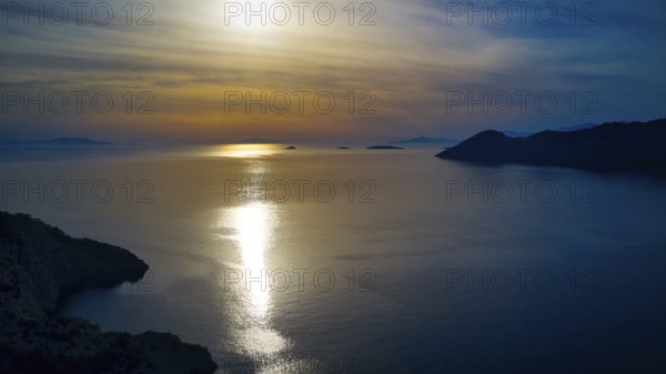 Drone shot, Fascinating sunset with light reflection in the water, Holy Week, Bay of Panormitis, Panormitis Monastery, Symi, Dodecanese, Greek Islands, Greece