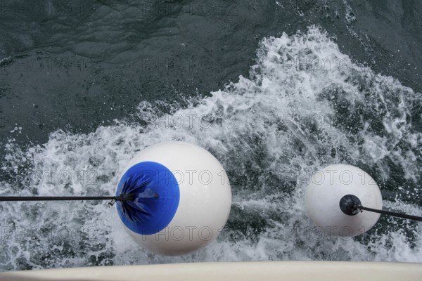 White buoys with blue markings float on moving water with whitecaps, Montenegro